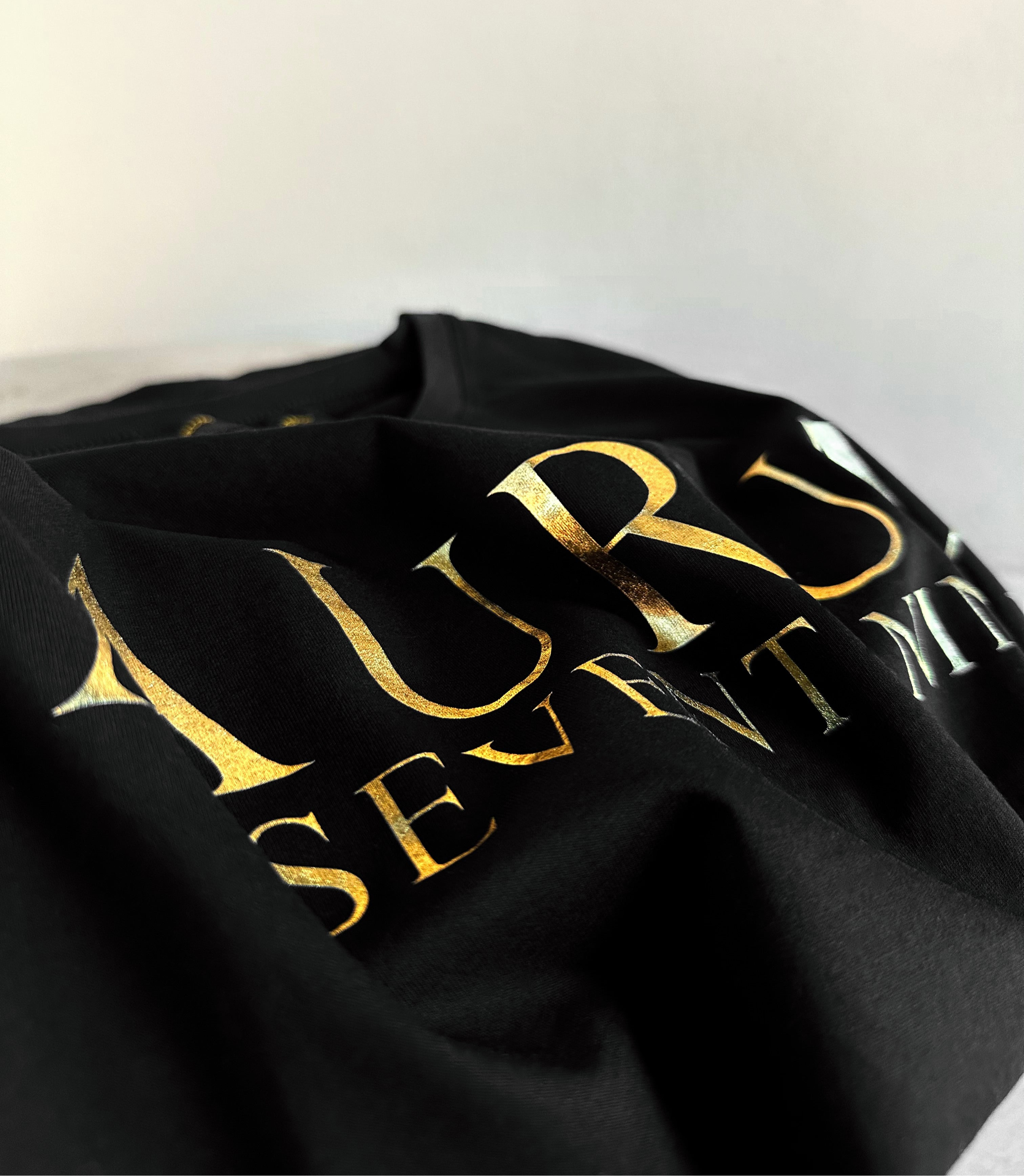 Aurum Seventy-nine: Foto vista da vicino della T-shirt Round Neck Aurum Classic Black, con focus sul logo dorato al centro.